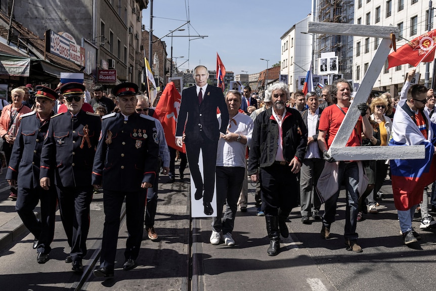 People marching in Belgrade carry a cut out of Vladimir Putin and a 'Z' sign.