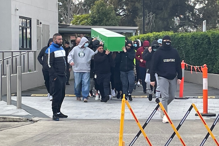 A coffin is carried by a group of men