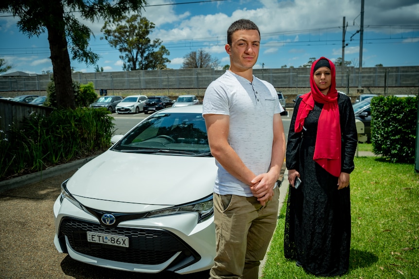 Ethan Jabbor and Huma Naz standing side by side next to a white Corolla.