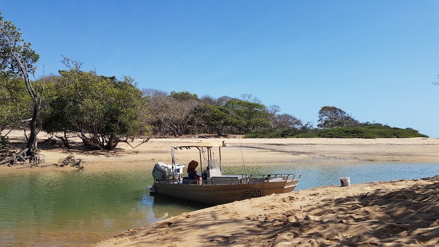 A photo of a small fishing vessel in a river mouth.