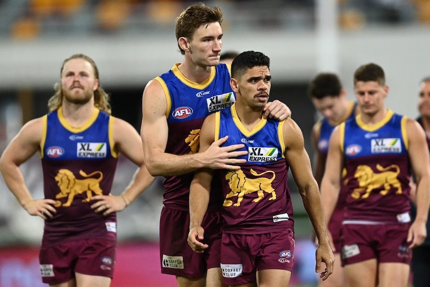 Brisbane Lions AFL players leave the field after a loss in a 2020 match.
