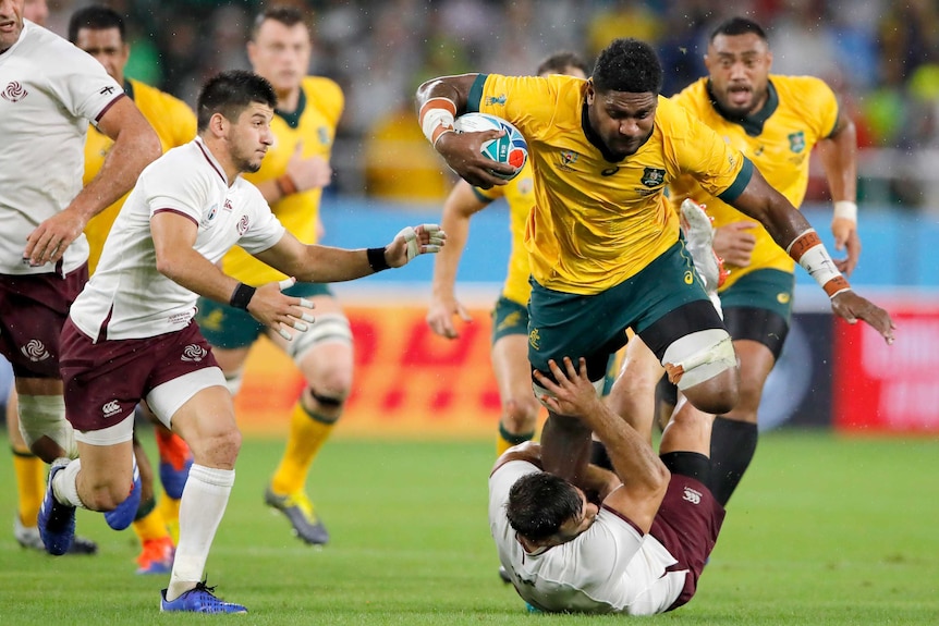 A Wallabies player runs the ball at a Georgian opponent at the Rugby World Cup.
