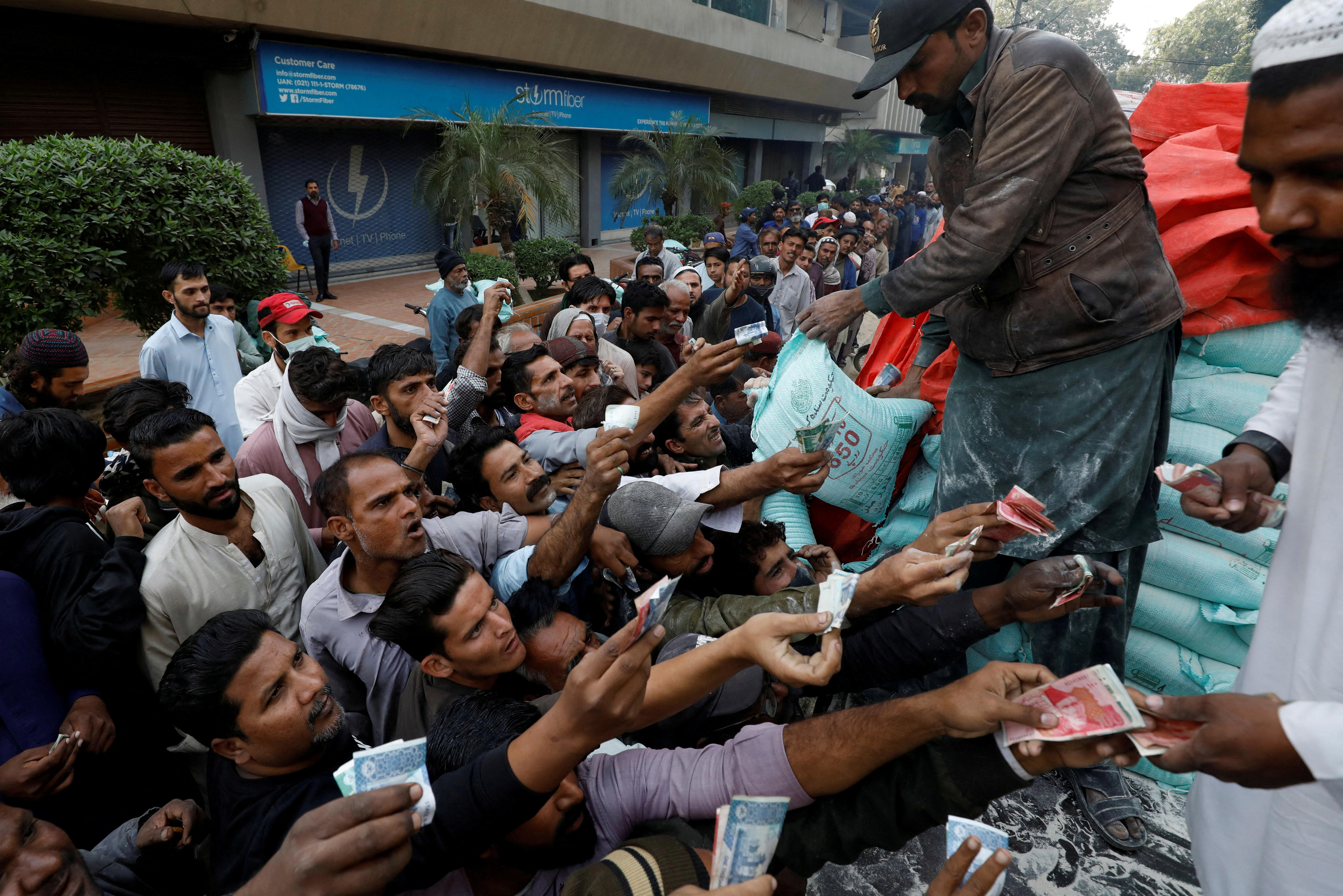 Picture of a group of men reaching out to buy bags of flour in Pakistan