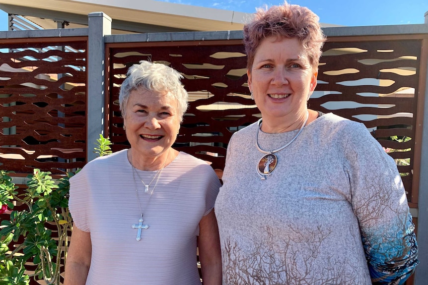 Two middle-aged women smiling in an outdoor setting