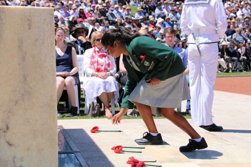 A student lays a poppy at the Remembrance Day National Service in Canberra.