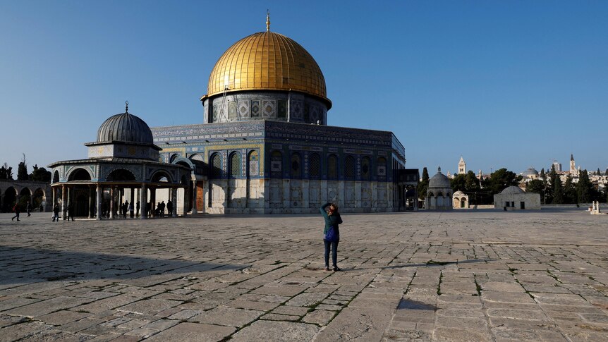 A visitor takes a picture next to the Dome of the Rock.