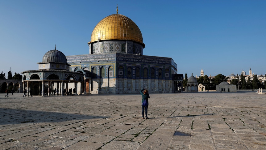 A visitor takes a picture next to the Dome of the Rock.