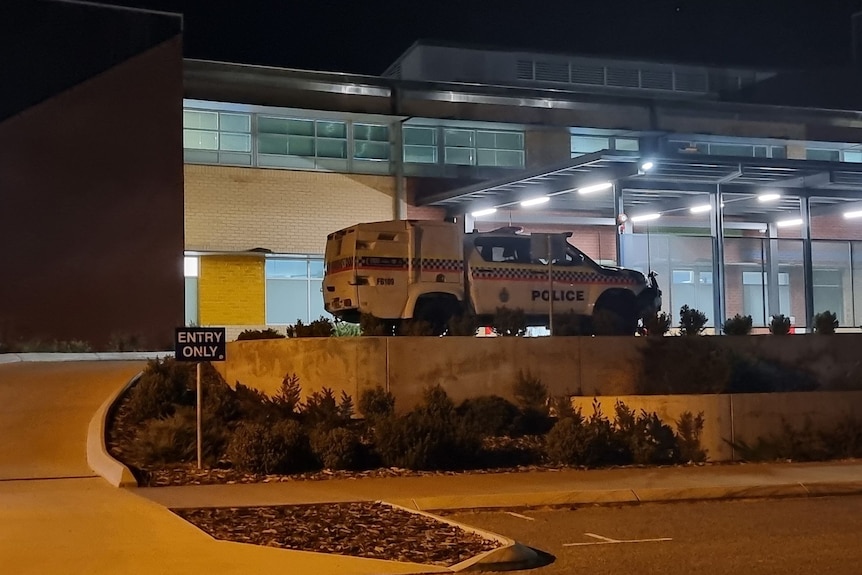 A police car parked outside a hospital emergency department at night. 