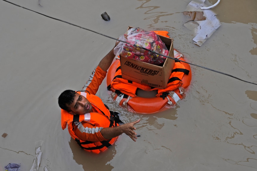 Aid workers flood relief goods on a floatation device in flood waters.