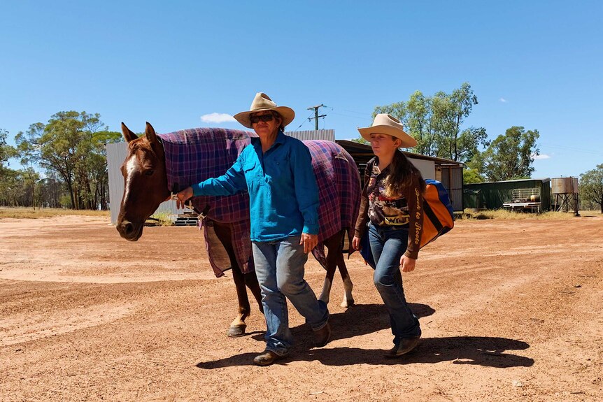 Jacky O'Dell and her 12-year-old daughter at their property Toarbee, in western Queensland walking in the yard with their horse.