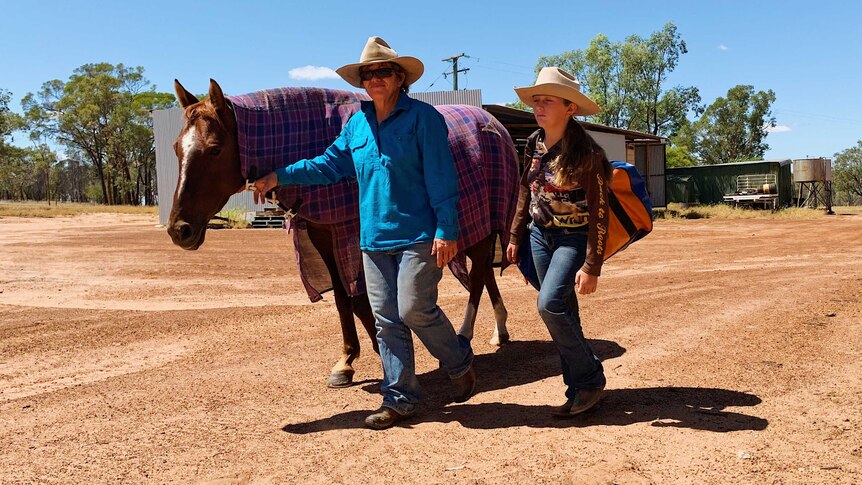 Jacky O'Dell and her 12-year-old daughter at their property Toarbee, in western Queensland walking in the yard with their horse.