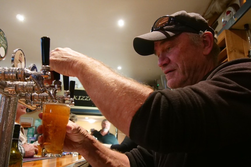 A man pulling a beer at a bar tap in a pub.