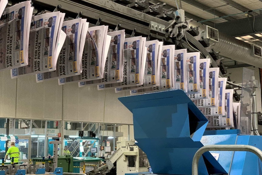Printed newspapers hanging in a line.