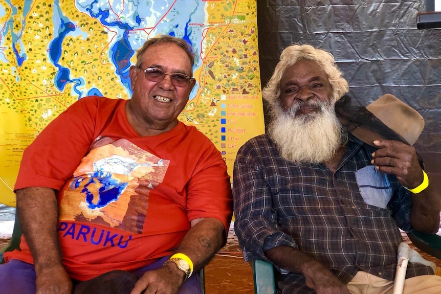 Two indigenous men sitting together. The man on the right has a long white beard.