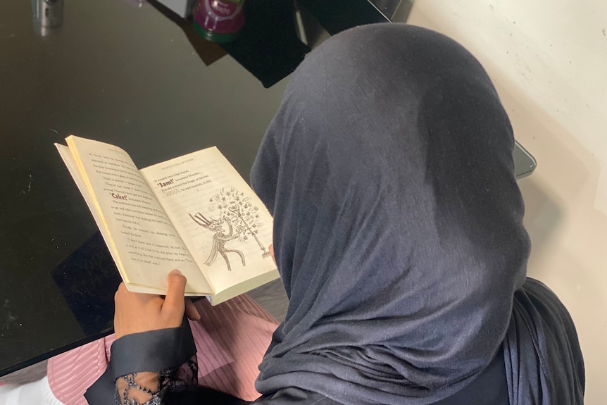 A girl in a hijab reading a book