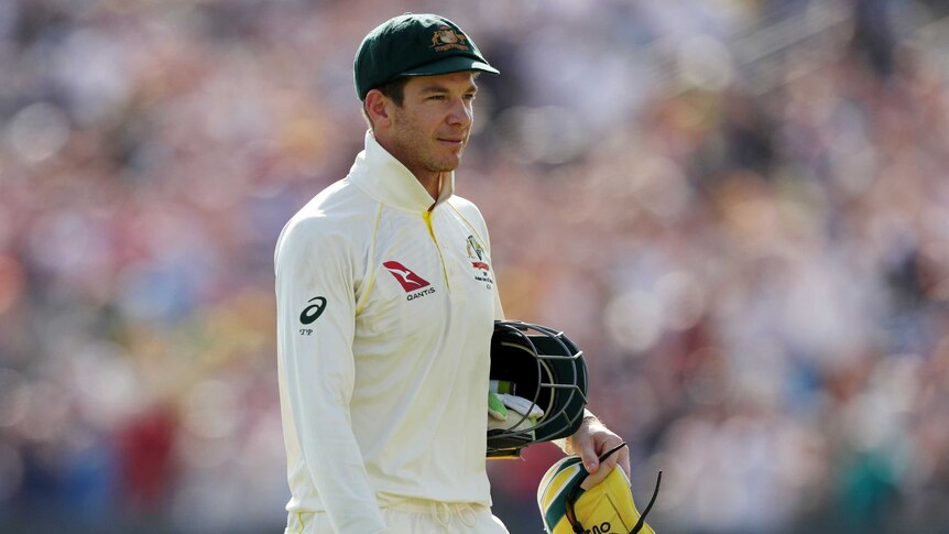 Tim Paine walks with his helmet under his arm and wicketkeeping gloves in his hand