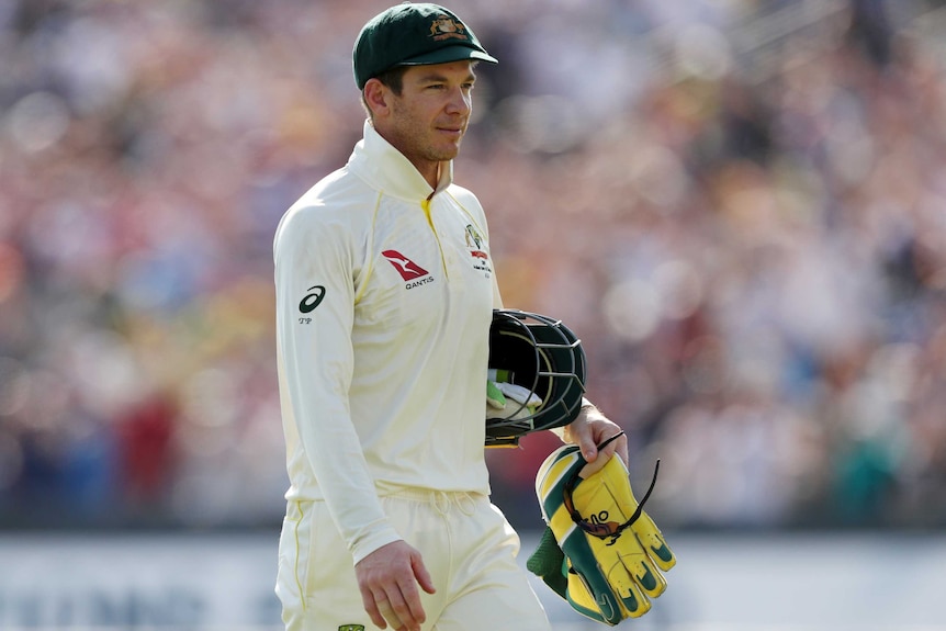 Tim Paine walks with his helmet under his arm and wicketkeeping gloves in his hand