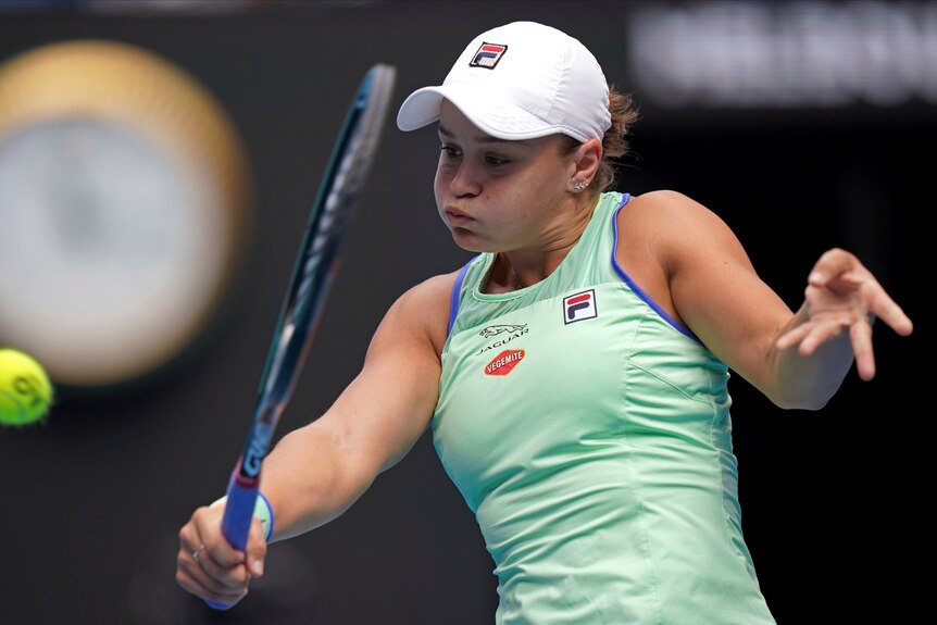 Ash Barty puffs out her cheeks and plays a one-handed back hand shot
