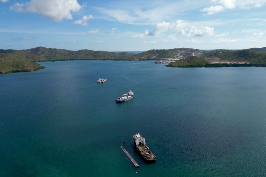 Three ships in the ocean with the coast of Port Moresby in the background.