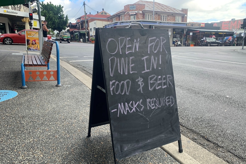 Sign outside a restaurant at West End in Brisbane saying 'open for dine in! Food and beer - masks required'