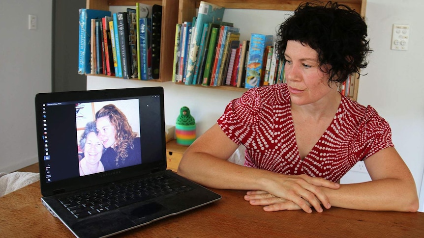 Josie Dietrich looking at a photo of herself with her mum, who died of breast cancer