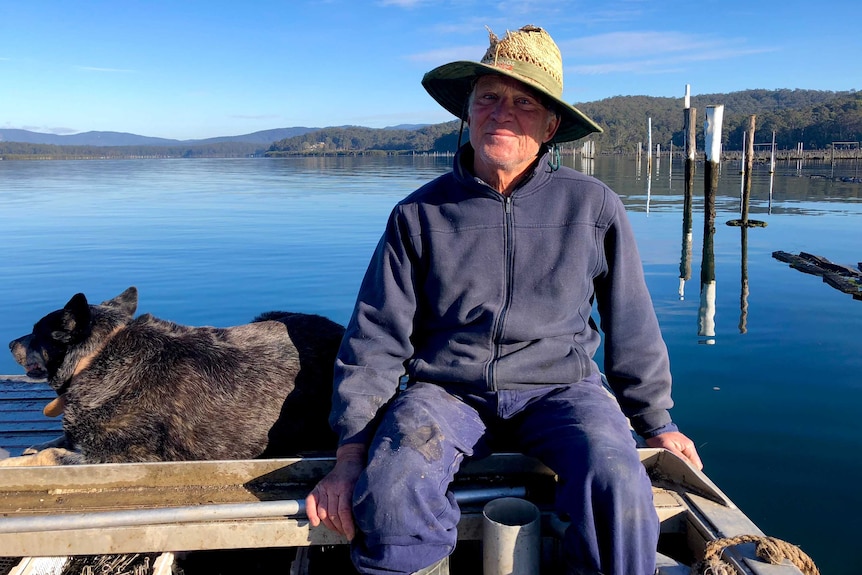 Oyster grower Kevin McAsh relaxes on the oyster punt with his dog Buzz on the Clyde River