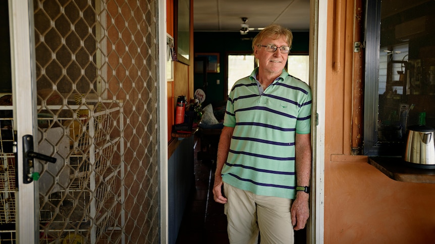 A man stands in a doorway looking off centre.