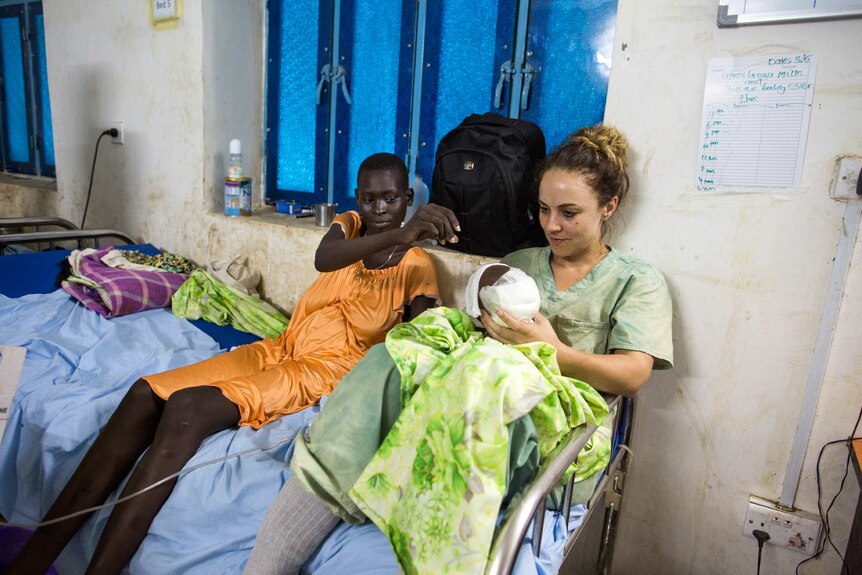 Nurse Jessica Hazelwood holds baby Nyanene as the child's mother watches.