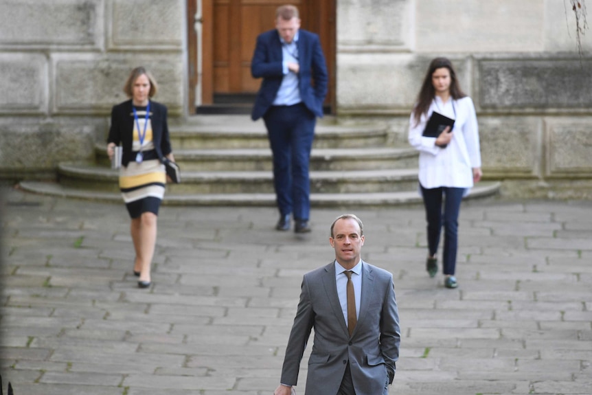 Raab with other colleagues walking at a distance.