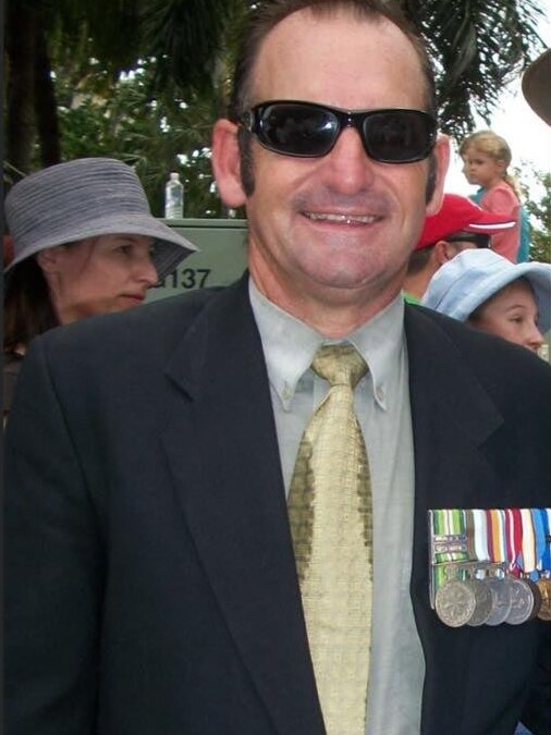 Man wears sun glasses, smiling wears medals on the left hand side of his black blazer