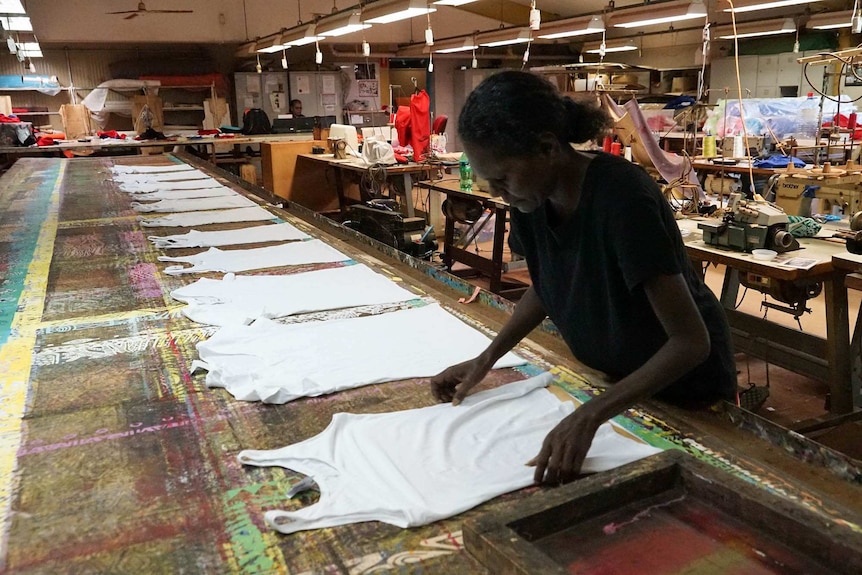 A woman works on a tshirt in a printing shop
