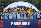 Melbourne City players celebrate while holding up the A-League premiership plate.