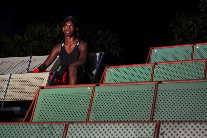A photo of Indigenous boxer Stephen Tipungwuti sitting in the stands at the Bush Church Boxing Club.