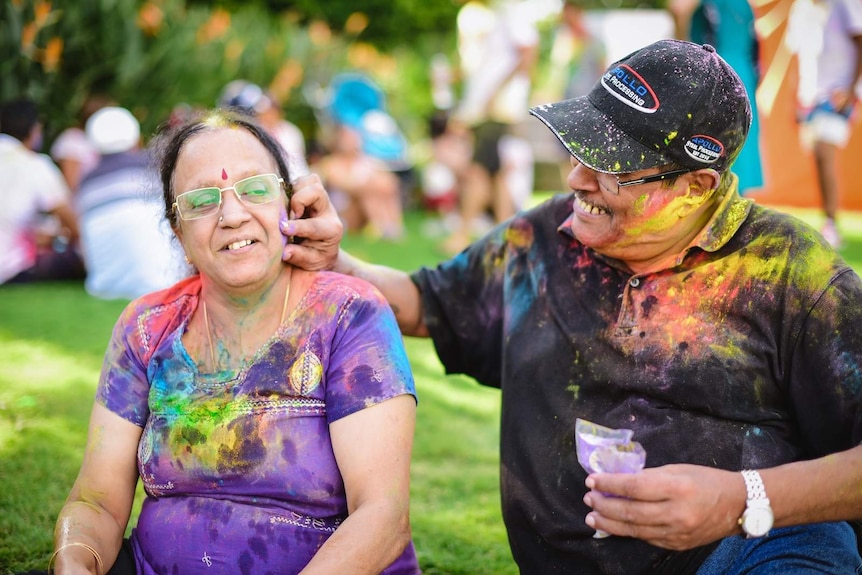 A husband dabs colour on his wife's face at Brisbane's Festival of Colours