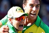 Pat Cummins's eyes are wide as he celebrates by clenching a fist and hugging Steve Smith. Aaron Finch approaches.