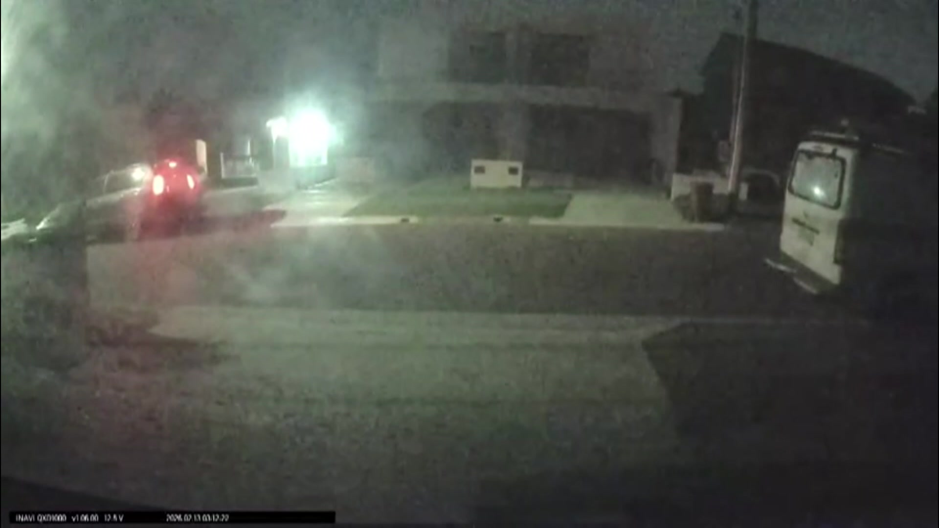 A car is parked at the front of a suburban house in the dark
