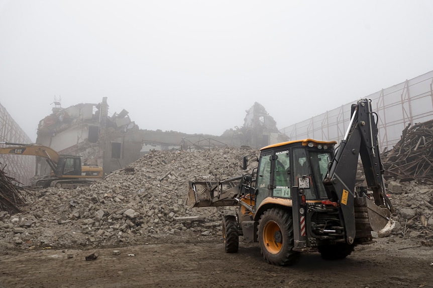 Municipal workers clear rubble and disassemble destroyed buildings at Mariupol theatre.