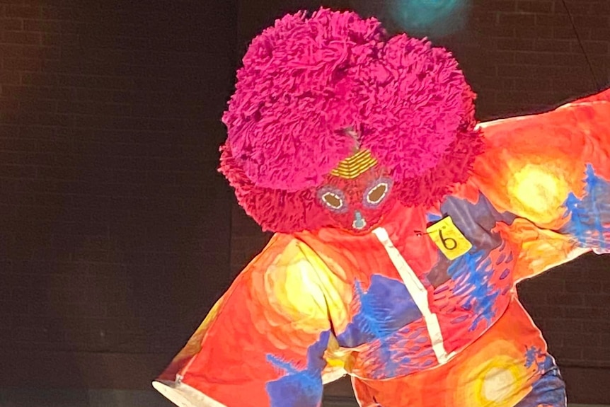 A person wearing a bright costume with a large mask and head ornament. 