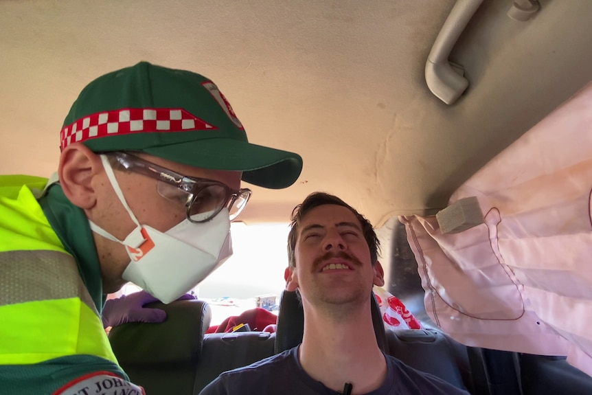 Paramedic in the back of a car with a man in pain.