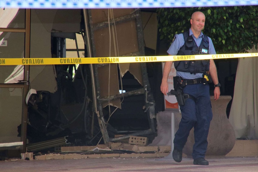 A police officer walks out of the damaged building at Joondalup Health Campus.