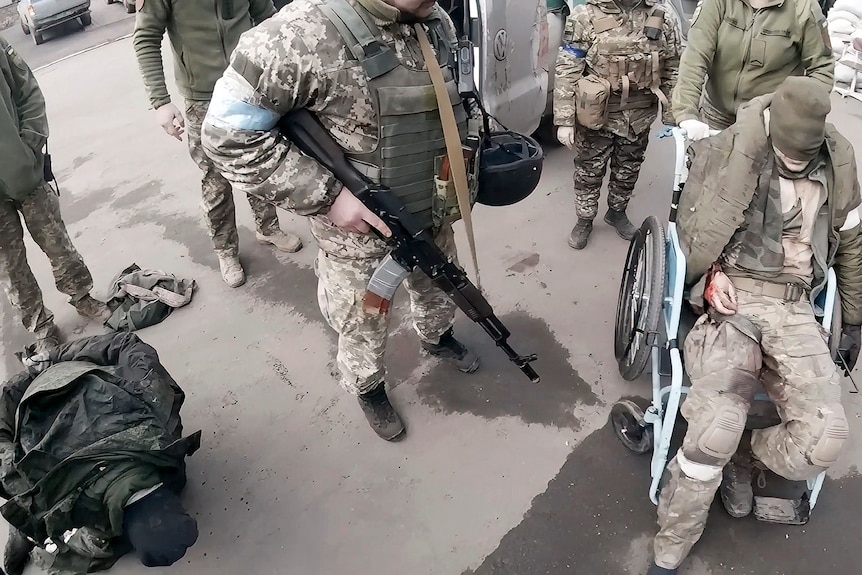 Body cam footage looking down at a Russian soldier in a wheelchair with his face covered as he arrives at a hospital. 