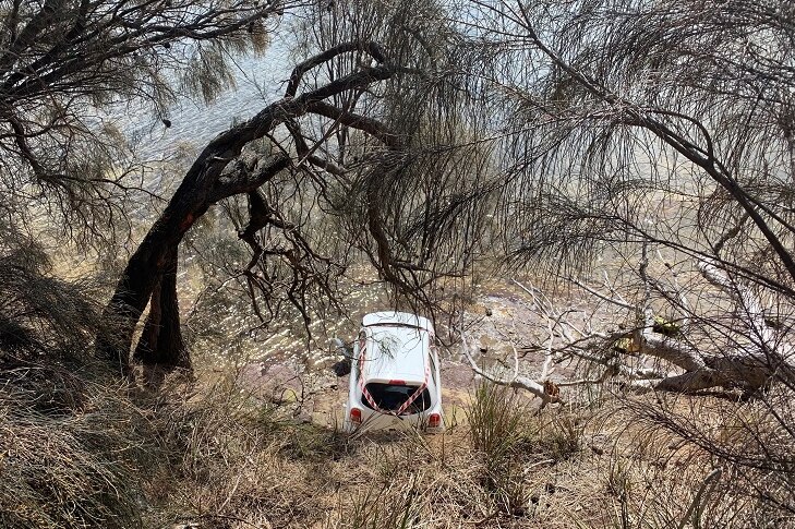 Car at the bottom of a cliff, seen from above.