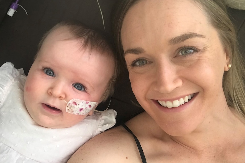 Baby with nasogastric tube and smiling woman