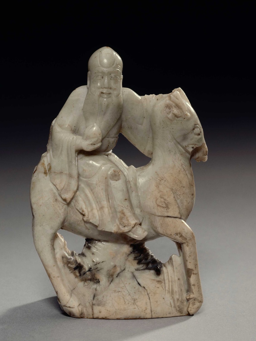 A figure of a Chinese man on a horse carrying a peach.