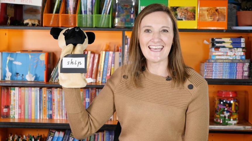 Female teacher smiles with puppet on hand