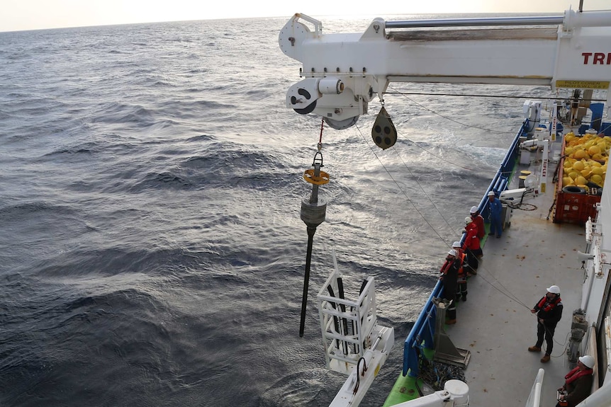 Core sample being transferred from sea to RV Investigator.