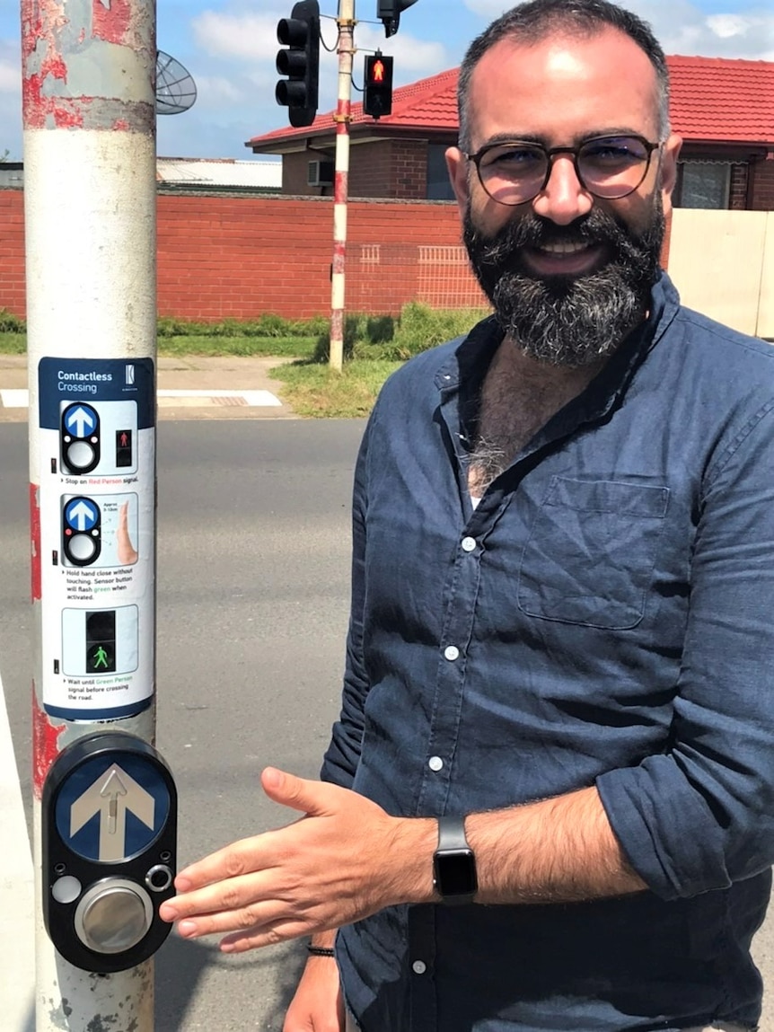 A man waving his hand over a touchless crossing button