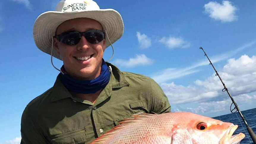 Jacob Bell on a boat holding a fish he has just caught