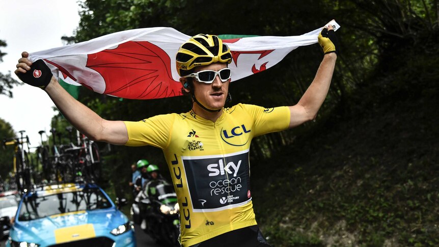 Britain's Geraint Thomas holds the flag of Wales wearing the overall leader's yellow jersey