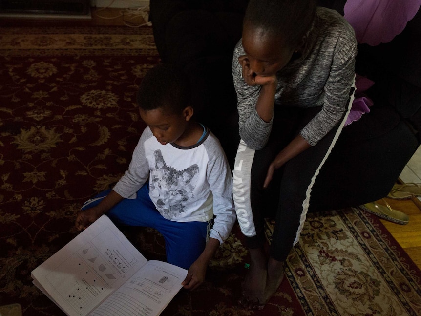 Monahil helps her younger brother with his NAPLAN study on the lounge room floor